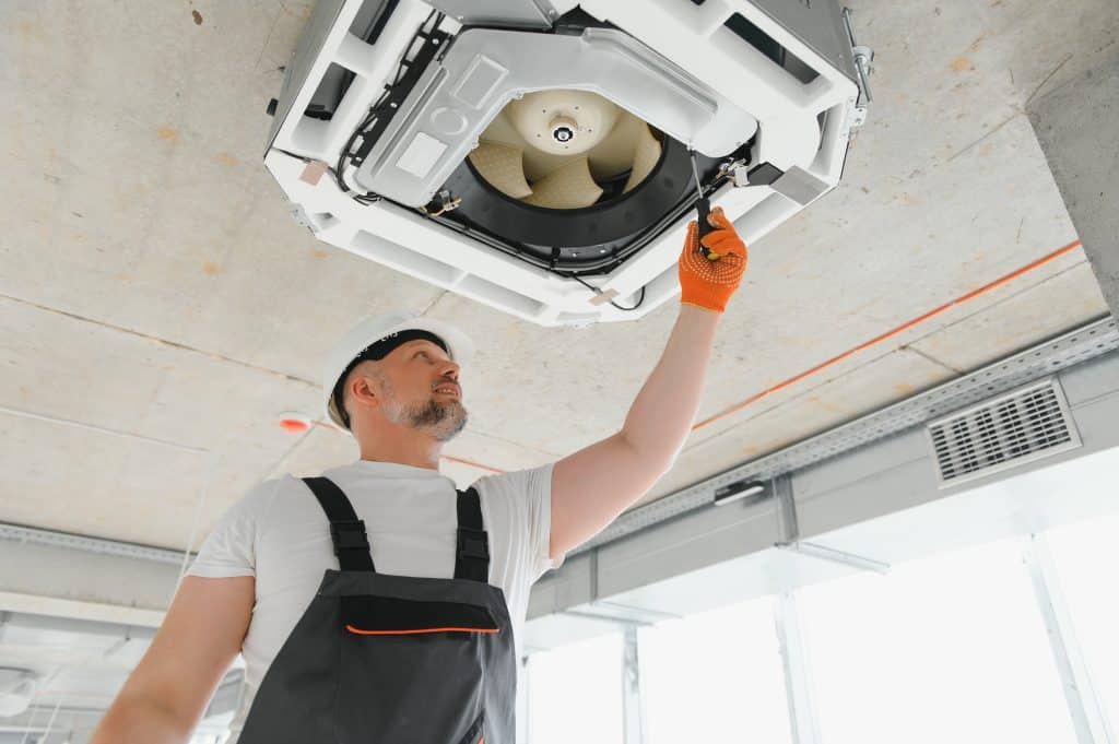 Worker repairing ceiling air conditioning unit